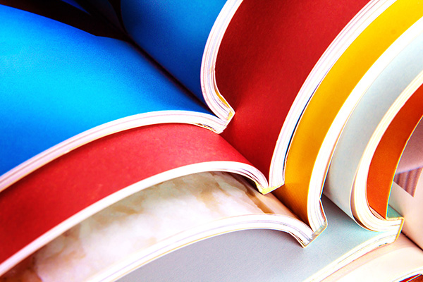 Close up view of multicolored pages inside several open booklets showing the perfect (glued) binding of the booklets