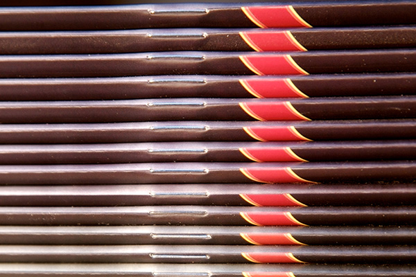 Close up view of brown magazines with a red and yellow highlight showing the saddlestitch (stapled) binding